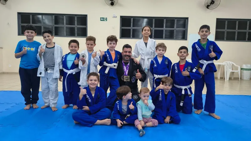 Turma de crianças do projeto de Jiu-Jitsu reunida com o sensei no salão social